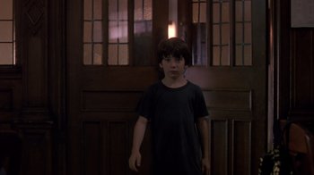 Movie still from “Searching for Bobby Fischer” (1993), directed by Steven Zaillian – A boy standing in front of a wooden door; Medium shot, Low angle