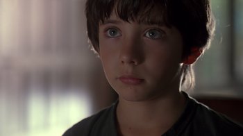 Movie still from “Searching for Bobby Fischer” (1993), directed by Steven Zaillian – A young boy with blue eyes stares into the camera; Close Up shot, Over the shoulder angle