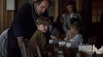 Movie still from “Searching for Bobby Fischer” (1993), directed by Steven Zaillian – A man standing next to a boy at a dinner table; Medium shot, Over the shoulder angle