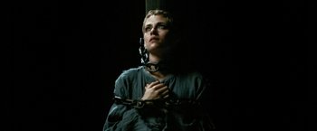 Movie still from “Seberg” (2019), directed by Benedict Andrews – A woman chained to a cross with her hands over her chest; Close Up shot, Low angle