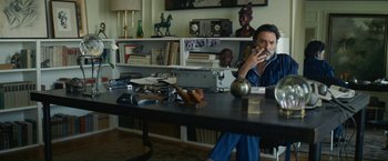 Movie still from “Seberg” (2019), directed by Benedict Andrews – A man sitting at a table talking on a phone; Medium shot, Low angle