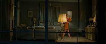 Movie still from “Seberg” (2019), directed by Benedict Andrews – A woman standing in front of a lamp in a room; Wide shot, Over the shoulder angle