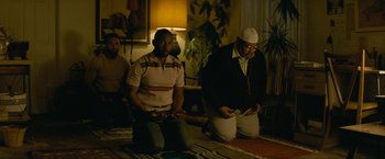 Movie still from “Seberg” (2019), directed by Benedict Andrews – Two men sitting on the ground in a room; Medium shot, Low angle