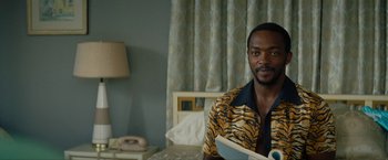 Movie still from “Seberg” (2019), directed by Benedict Andrews – A man sitting on a bed in a room; Medium shot, Over the shoulder angle