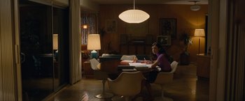 Movie still from “Seberg” (2019), directed by Benedict Andrews – A woman sitting at a table in front of a lamp; Wide shot, High angle
