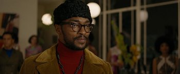 Movie still from “Seberg” (2019), directed by Benedict Andrews – A person wearing glasses and a hat; Close Up shot, Over the shoulder angle