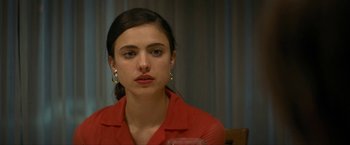 Movie still from “Seberg” (2019), directed by Benedict Andrews – A young woman wearing a red shirt is sitting in front of a curtain; Close Up shot, Over the shoulder angle
