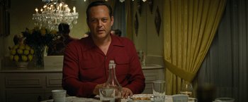 Movie still from “Seberg” (2019), directed by Benedict Andrews – A man sitting at a table with a bottle of wine; Medium shot, Over the shoulder angle