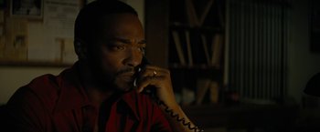 Movie still from “Seberg” (2019), directed by Benedict Andrews – A man talking on a phone while sitting in a room; Close Up shot, Low angle