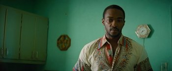 Movie still from “Seberg” (2019), directed by Benedict Andrews – A man in a colorful shirt standing in front of a green wall; Close Up shot, Low angle