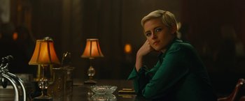 Movie still from “Seberg” (2019), directed by Benedict Andrews – A woman sitting at a table in front of a lamp; Medium shot, High angle