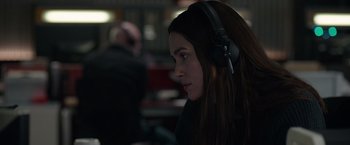 Movie still from “Official Secrets” (2019), directed by Gavin Hood – A woman wearing a black jacket and headphones; Close Up shot, Over the shoulder angle