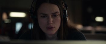 Movie still from “Official Secrets” (2019), directed by Gavin Hood – A woman wearing headphones looking at a computer screen; Close Up shot, Over the shoulder angle