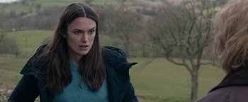 Movie still from “Official Secrets” (2019), directed by Gavin Hood – A woman standing in a field with a bird on her shoulder; Close Up shot, Over the shoulder angle