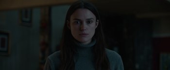 Movie still from “Official Secrets” (2019), directed by Gavin Hood – A woman with long black hair wearing a gray sweater; Close Up shot, Low angle