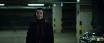 Movie still from “Official Secrets” (2019), directed by Gavin Hood – A woman wearing a hijab standing in a parking lot; Medium shot, Low angle