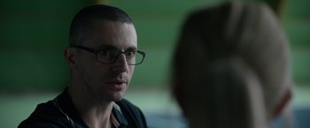 Movie still from “Official Secrets” (2019), directed by Gavin Hood – A person wearing glasses; Close Up shot, Over the shoulder angle