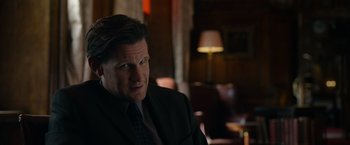 Movie still from “Official Secrets” (2019), directed by Gavin Hood – A person wearing a suit and tie; Close Up shot, Over the shoulder angle