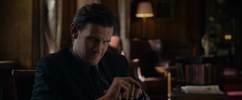 Movie still from “Official Secrets” (2019), directed by Gavin Hood – A person wearing a suit and tie; Close Up shot, Over the shoulder angle