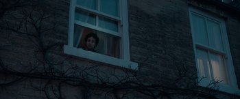 Movie still from “Official Secrets” (2019), directed by Gavin Hood – A man looking out of a window at night; Medium shot, Over the shoulder angle