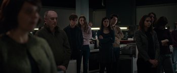 Movie still from “Official Secrets” (2019), directed by Gavin Hood – A group of young people standing in a room; Medium shot, Over the shoulder angle