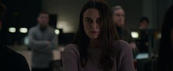 Movie still from “Official Secrets” (2019), directed by Gavin Hood – A woman with long dark brown hair wearing a sweater; Medium shot, Over the shoulder angle