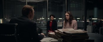 Movie still from “Official Secrets” (2019), directed by Gavin Hood – A group of people sitting at a table in front of a window; Medium shot, Over the shoulder angle