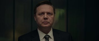 Movie still from “Official Secrets” (2019), directed by Gavin Hood – A person wearing a suit and tie; Close Up shot, Low angle
