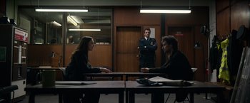 Movie still from “Official Secrets” (2019), directed by Gavin Hood – A man and a woman sitting at a table in front of another man; Wide shot, Over the shoulder angle