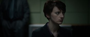 Movie still from “Official Secrets” (2019), directed by Gavin Hood – A woman with short brown hair wearing a black jacket; Close Up shot, Over the shoulder angle