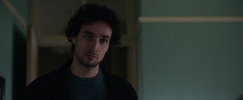 Movie still from “Official Secrets” (2019), directed by Gavin Hood – A man with a beard is looking at the camera; Close Up shot, Over the shoulder angle