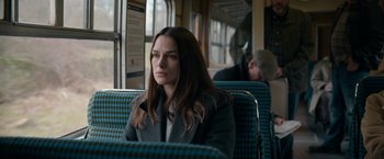 Movie still from “Official Secrets” (2019), directed by Gavin Hood – A woman is sitting on a train looking out the window; Medium shot, Over the shoulder angle