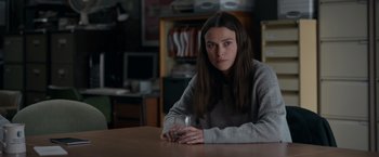 Movie still from “Official Secrets” (2019), directed by Gavin Hood – A woman sitting at a table holding a glass of wine; Medium shot, Over the shoulder angle