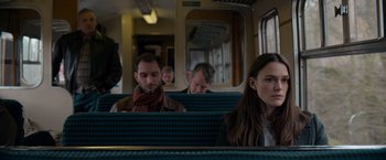 Movie still from “Official Secrets” (2019), directed by Gavin Hood – A group of people sitting in a train car; Medium shot, Over the shoulder angle