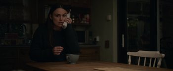 Movie still from “Official Secrets” (2019), directed by Gavin Hood – A woman sitting at a table talking on a cell phone; Medium shot, High angle