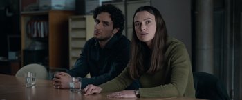 Movie still from “Official Secrets” (2019), directed by Gavin Hood – A man and a woman sitting at a wooden table; Medium shot, Over the shoulder angle