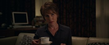 Movie still from “Official Secrets” (2019), directed by Gavin Hood – A woman sitting in a chair holding a cup of coffee; Close Up shot, Over the shoulder angle