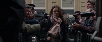 Movie still from “Official Secrets” (2019), directed by Gavin Hood – A woman is being interviewed by a crowd of people; Medium shot, Over the shoulder angle