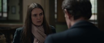 Movie still from “Official Secrets” (2019), directed by Gavin Hood – A woman wearing a scarf looking at a man in a suit in front of a mirror; Close Up shot, Over the shoulder angle