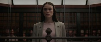 Movie still from “Official Secrets” (2019), directed by Gavin Hood – A woman standing in front of an iron gate; Medium shot, Low angle