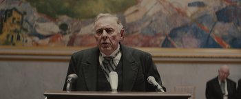 Movie still from “Selma” (2014), directed by Ava DuVernay – An older man in a suit and tie is speaking at a podium; Medium shot, Over the shoulder angle