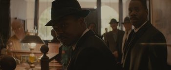 Movie still from “Selma” (2014), directed by Ava DuVernay – A man wearing a suit and a hat in front of other men; Close Up shot, Over the shoulder angle