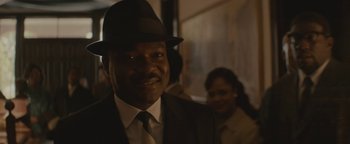 Movie still from “Selma” (2014), directed by Ava DuVernay – A man wearing a suit and a hat smiling for the camera; Close Up shot, Over the shoulder angle