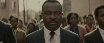 Movie still from “Selma” (2014), directed by Ava DuVernay – A man wearing a suit and tie standing in front of a group of people; Close Up shot, Low angle