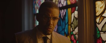 Movie still from “Selma” (2014), directed by Ava DuVernay – A person wearing a suit and glasses; Close Up shot, Over the shoulder angle