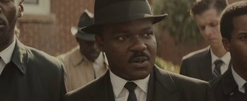 Movie still from “Selma” (2014), directed by Ava DuVernay – A man in a suit and hat is looking at the camera; Close Up shot, Over the shoulder angle