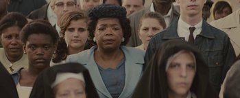 Movie still from “Selma” (2014), directed by Ava DuVernay – An older woman is standing among a crowd of people; Close Up shot, Over the shoulder angle