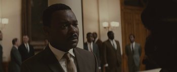 Movie still from “Selma” (2014), directed by Ava DuVernay – A man in a suit and tie standing in front of a group of men; Close Up shot, Over the shoulder angle