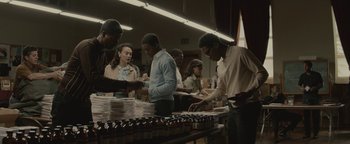 Movie still from “Selma” (2014), directed by Ava DuVernay – A group of people standing around a table with food; Medium shot, High angle