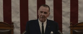 Movie still from “Selma” (2014), directed by Ava DuVernay – An older man wearing a suit and tie in front of an american flag; Close Up shot, Low angle